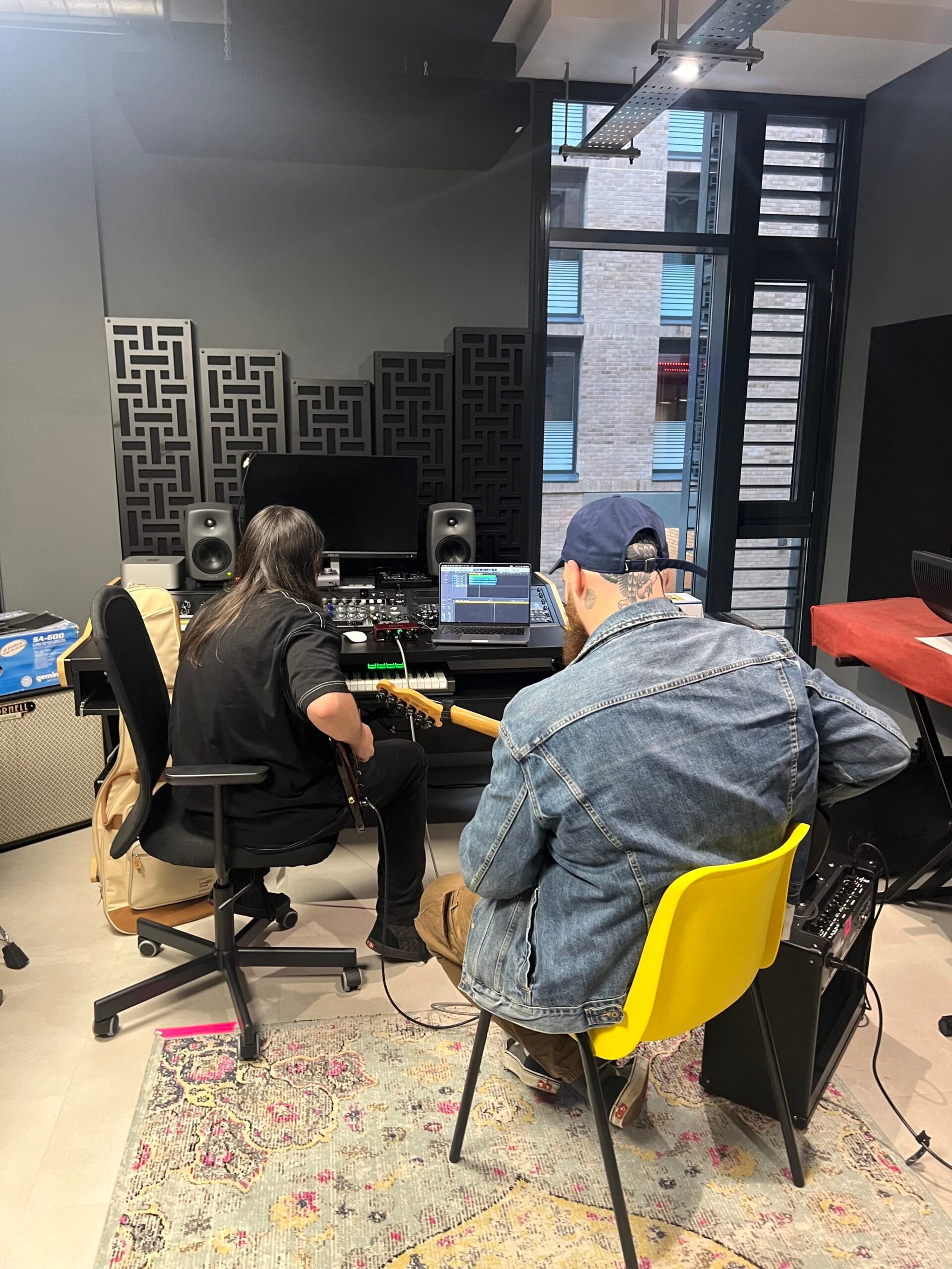 Musician recording guitar with a producer in a mobile, home studio style setup, showing how to record music with a flexible, budget-friendly setup.