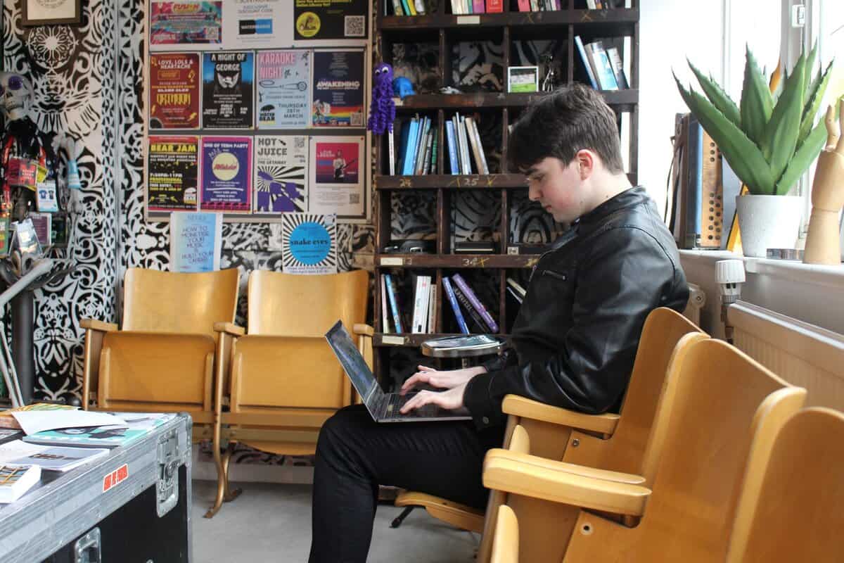 Independent artist at WaterBear Brighton HQ working on a laptop, preparing outreach emails to music managers and artist management companies.