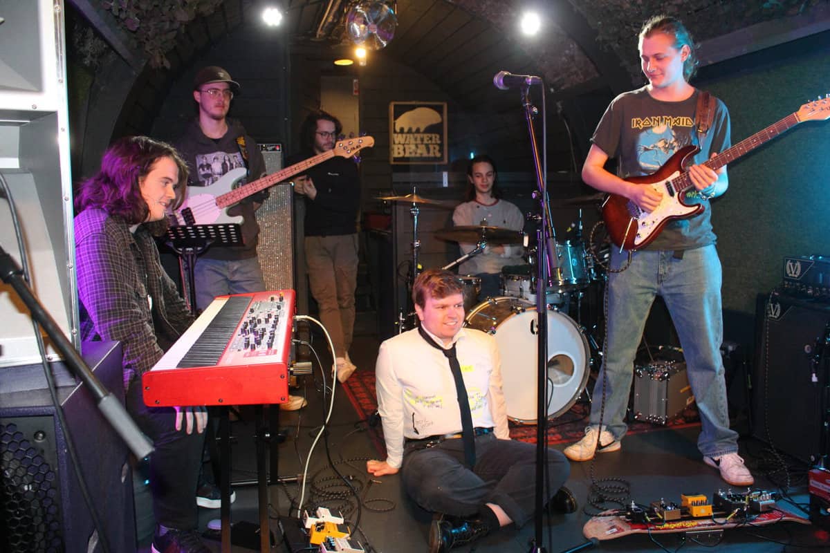 Independent artists rehearsing live on stage at a music venue, preparing for artist management opportunities and developing their music career.